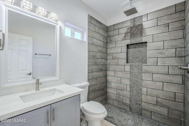 bathroom with vanity, tiled shower, and toilet