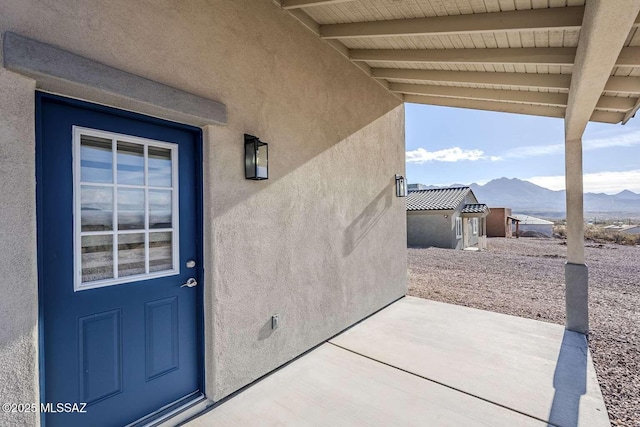 view of exterior entry with a patio and a mountain view