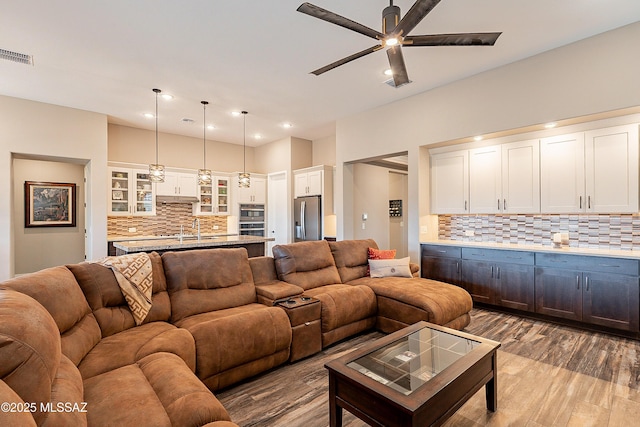 living room featuring ceiling fan, sink, and light hardwood / wood-style flooring