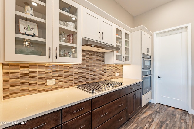 kitchen with appliances with stainless steel finishes, dark brown cabinets, white cabinets, dark hardwood / wood-style flooring, and decorative backsplash