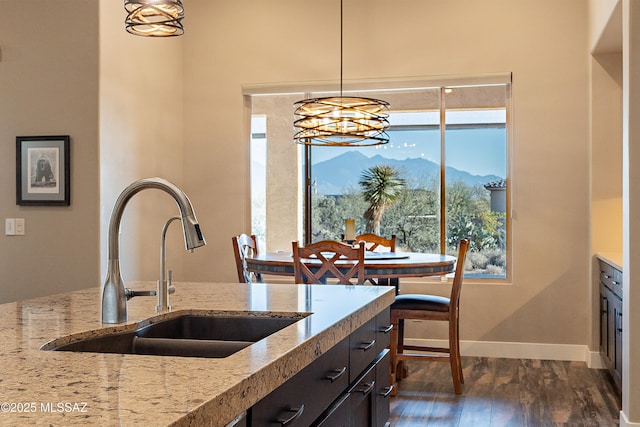 kitchen featuring sink, dark hardwood / wood-style flooring, hanging light fixtures, light stone counters, and a mountain view