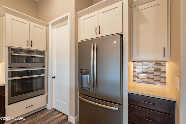 kitchen with stainless steel appliances, white cabinetry, tasteful backsplash, and dark hardwood / wood-style floors