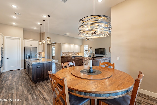 dining space featuring dark hardwood / wood-style flooring, a chandelier, and sink