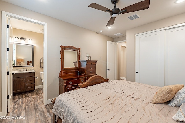 bedroom with ensuite bathroom, dark hardwood / wood-style floors, sink, ceiling fan, and a closet