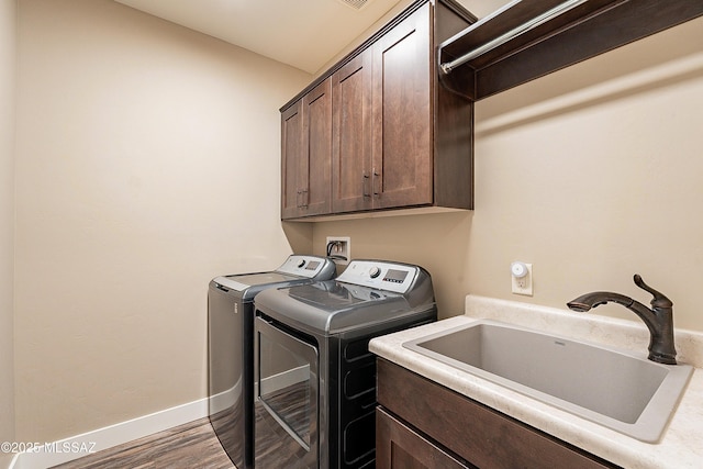 washroom with cabinets, dark hardwood / wood-style floors, washer and clothes dryer, and sink