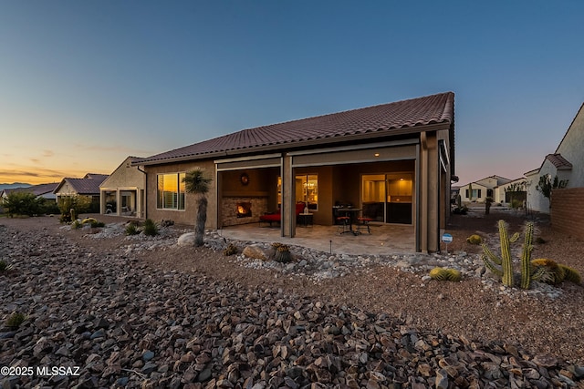 back house at dusk featuring a patio area