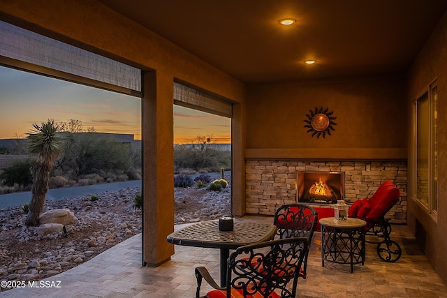 patio terrace at dusk featuring an outdoor stone fireplace