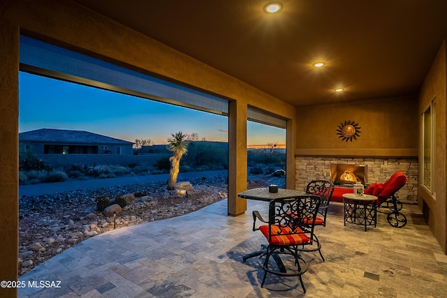 snow covered patio with an outdoor stone fireplace