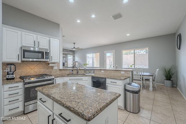 kitchen featuring stainless steel appliances, a kitchen island, white cabinets, and kitchen peninsula