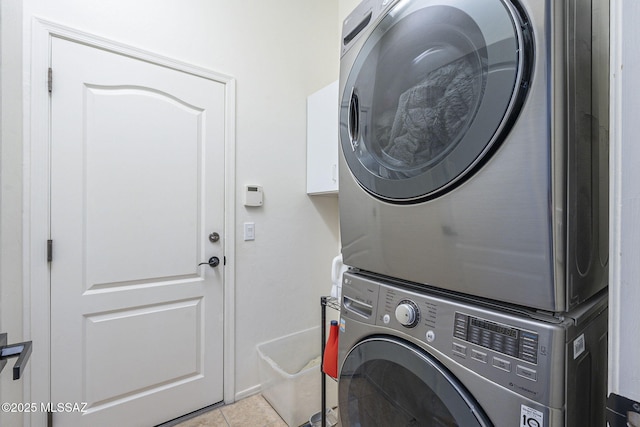 washroom with stacked washer / dryer and light tile patterned flooring