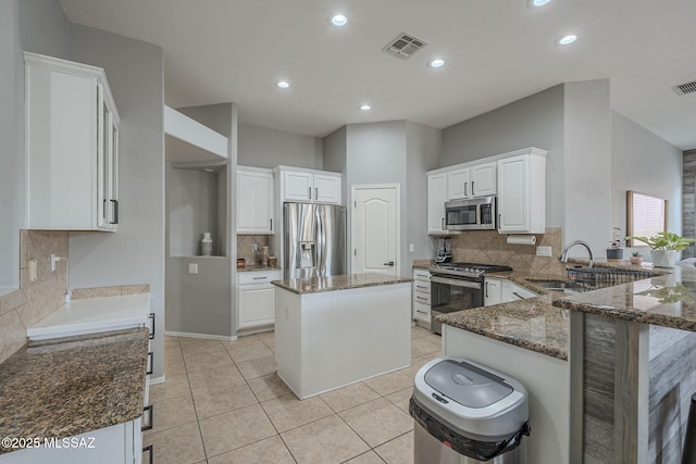 kitchen featuring white cabinetry, a center island, stainless steel appliances, and kitchen peninsula