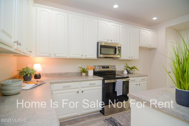 kitchen with white cabinetry, appliances with stainless steel finishes, and light hardwood / wood-style floors