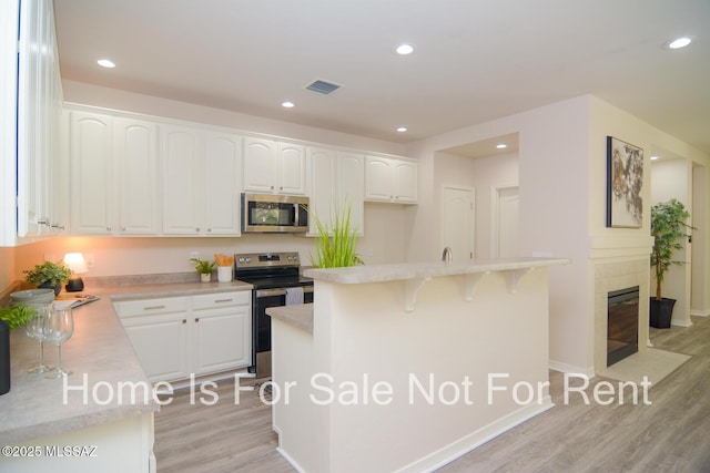 kitchen featuring white cabinetry, stainless steel appliances, a kitchen island, and light wood-type flooring