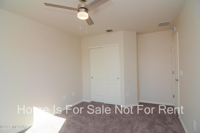 unfurnished bedroom with ceiling fan, dark carpet, and a closet