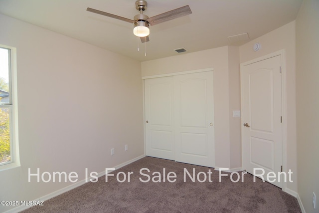 unfurnished bedroom featuring multiple windows, dark carpet, and a closet