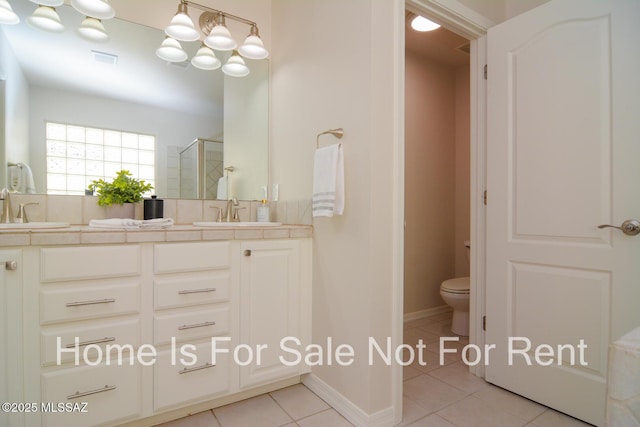 bathroom featuring vanity, a shower with door, tile patterned floors, and toilet