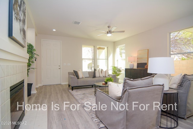 living room featuring ceiling fan, a fireplace, and light hardwood / wood-style flooring