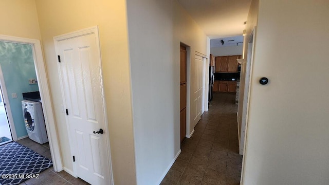 corridor with dark tile patterned flooring and washer / dryer