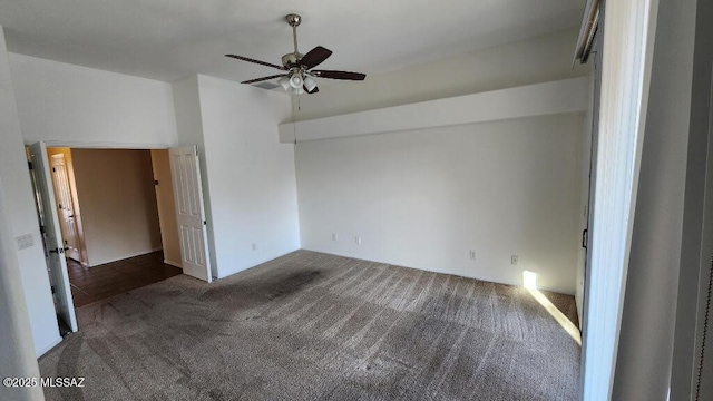 unfurnished bedroom with ceiling fan and dark carpet