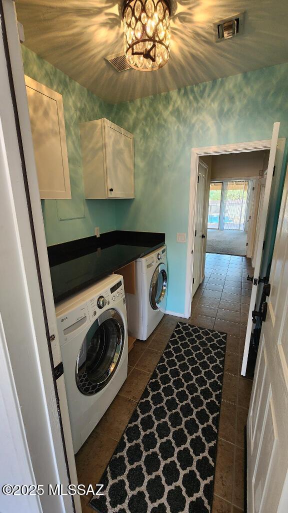 laundry area featuring separate washer and dryer, cabinets, and dark tile patterned floors