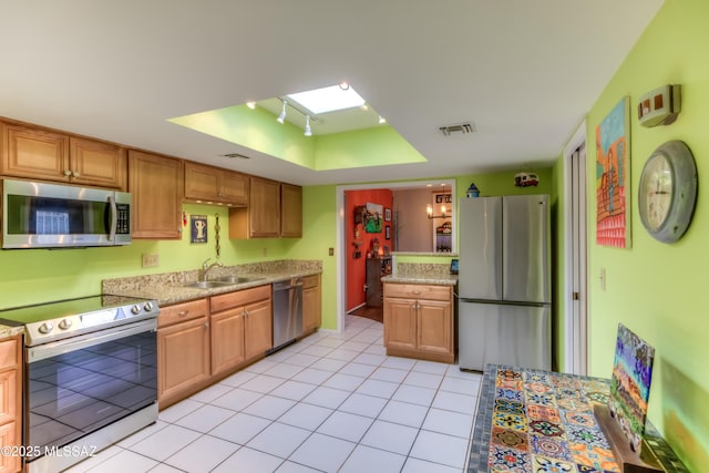 kitchen featuring light tile patterned flooring, sink, a tray ceiling, stainless steel appliances, and track lighting