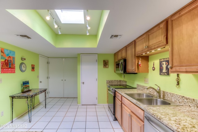 kitchen with sink, rail lighting, appliances with stainless steel finishes, light tile patterned flooring, and a raised ceiling