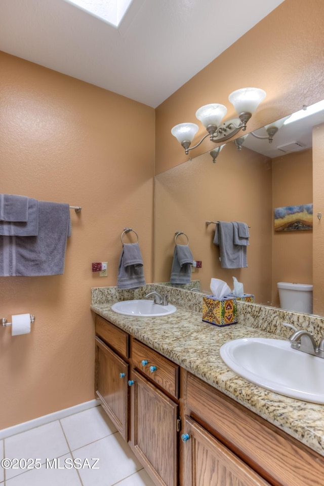 bathroom featuring a skylight, vanity, tile patterned floors, and toilet