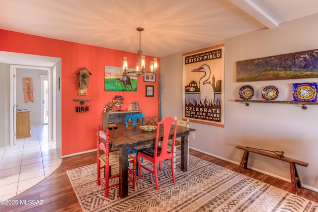 dining room featuring hardwood / wood-style flooring, beam ceiling, and a notable chandelier