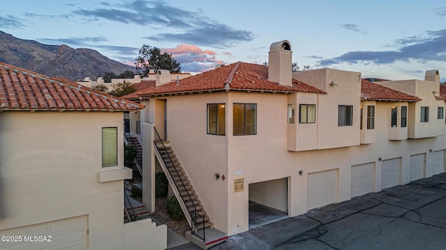 property exterior at dusk with a garage and a mountain view