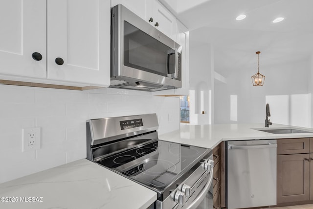 kitchen with sink, white cabinetry, appliances with stainless steel finishes, light stone countertops, and decorative backsplash