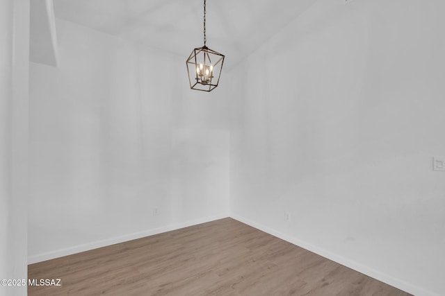 empty room with wood-type flooring and a chandelier