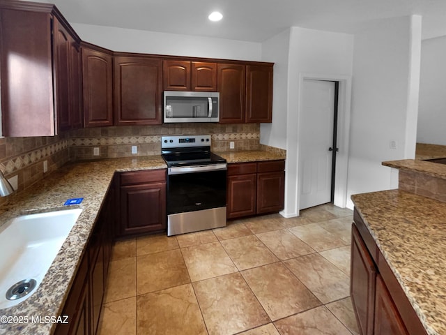 kitchen featuring stainless steel appliances, light stone countertops, sink, and decorative backsplash