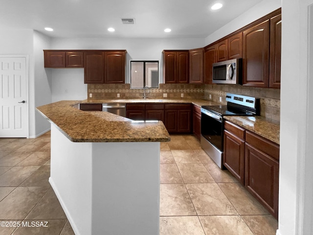 kitchen with a kitchen island, sink, dark stone countertops, backsplash, and stainless steel appliances