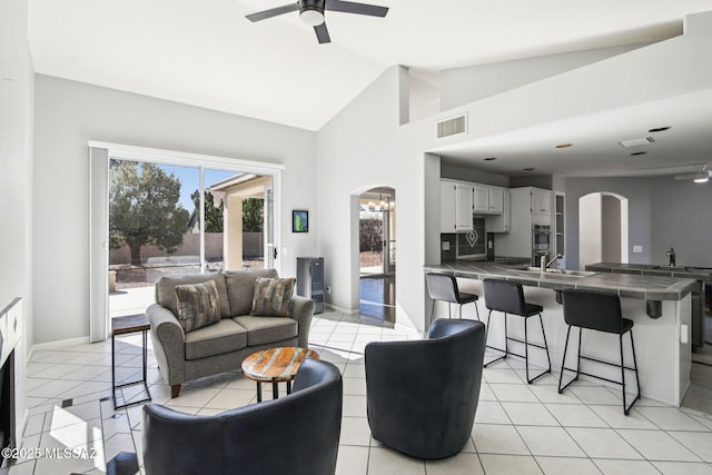 living room with lofted ceiling, sink, ceiling fan with notable chandelier, and light tile patterned floors