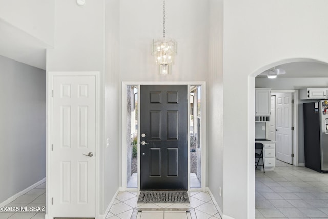 entrance foyer with a high ceiling, light tile patterned floors, and a chandelier