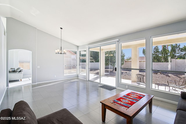 living room featuring tile patterned flooring, vaulted ceiling, a wealth of natural light, and an inviting chandelier