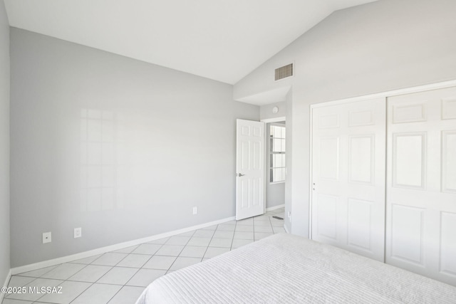 unfurnished bedroom with light tile patterned flooring, lofted ceiling, and a closet