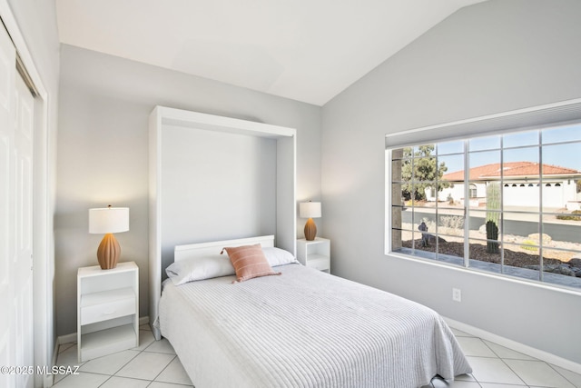 tiled bedroom with lofted ceiling and a closet