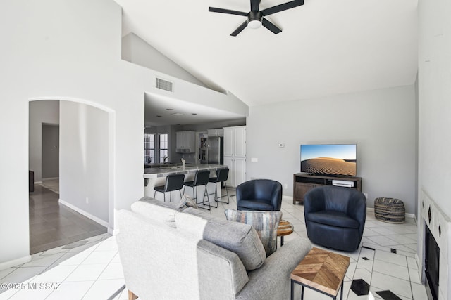 living room featuring light tile patterned floors, high vaulted ceiling, sink, and ceiling fan