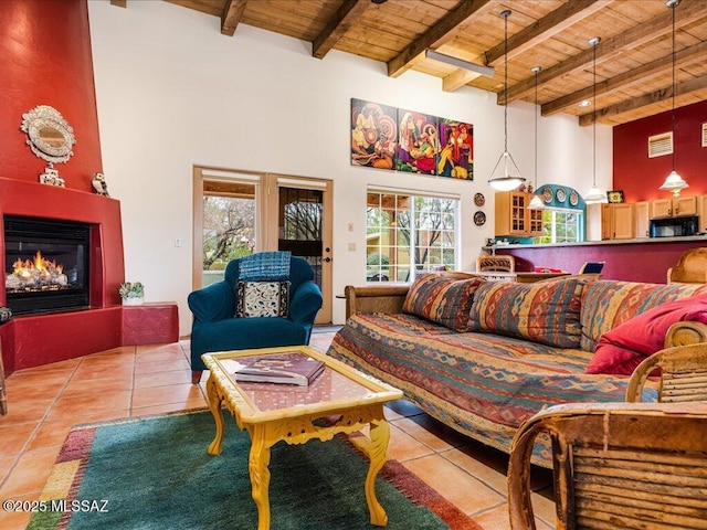 living room with beamed ceiling, light tile patterned flooring, a high ceiling, and wooden ceiling