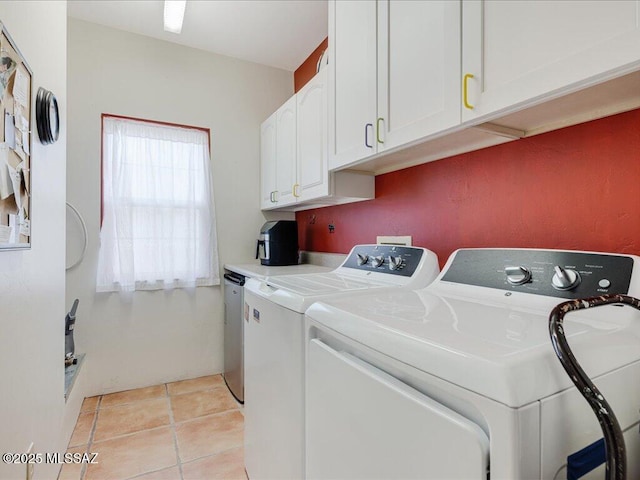 clothes washing area featuring light tile patterned floors, washing machine and dryer, and cabinets