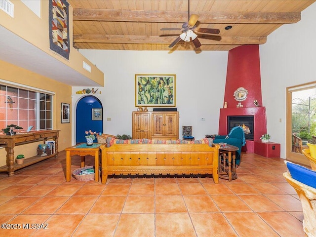 living room with ceiling fan, beam ceiling, a fireplace, wooden ceiling, and tile patterned floors