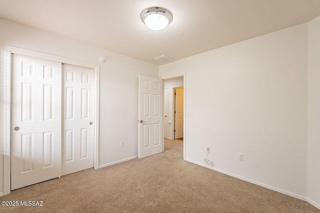 unfurnished bedroom featuring light carpet and a closet