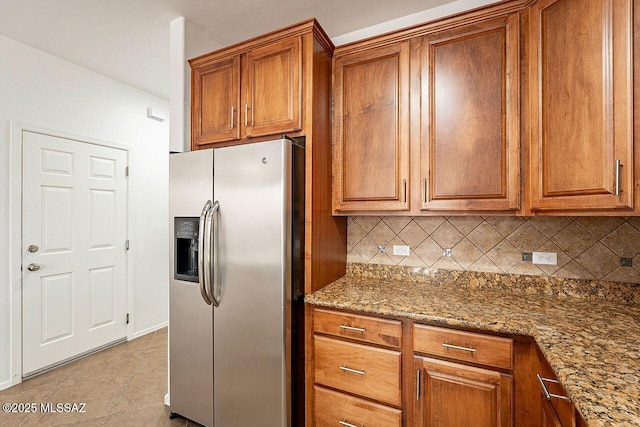 kitchen featuring decorative backsplash, light stone counters, and stainless steel fridge with ice dispenser