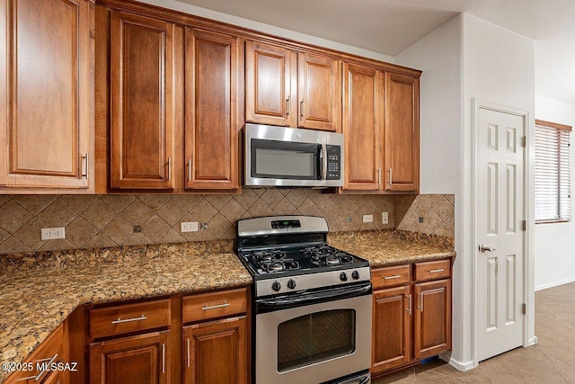 kitchen featuring backsplash, stainless steel appliances, light stone counters, and light tile patterned floors