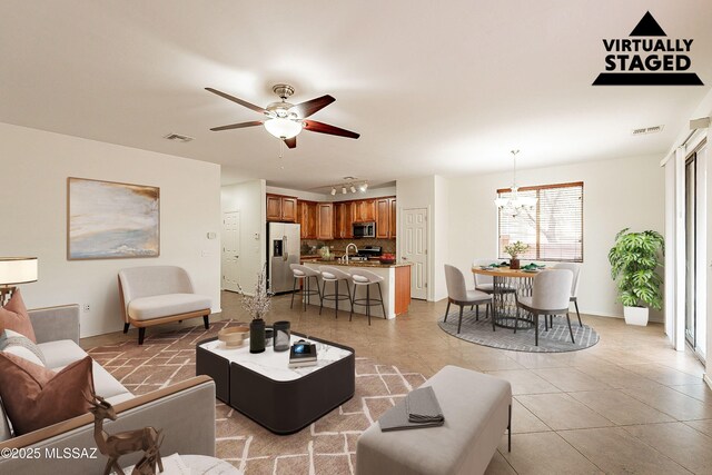 living room featuring ceiling fan with notable chandelier, light tile patterned floors, and sink