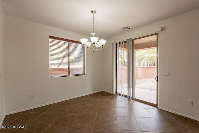 spare room with dark tile patterned floors and a notable chandelier