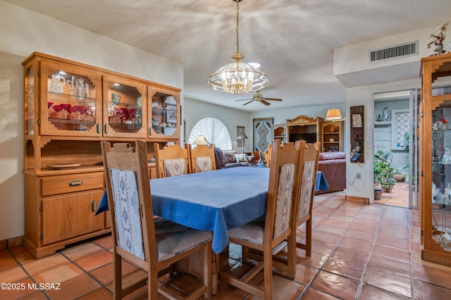 dining room with ceiling fan with notable chandelier, a textured ceiling, and light tile patterned floors