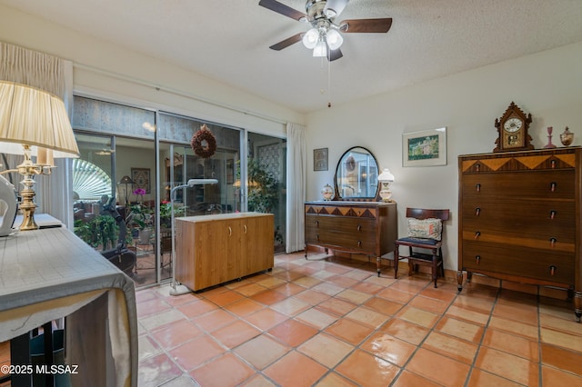 interior space featuring ceiling fan, light tile patterned floors, and a textured ceiling