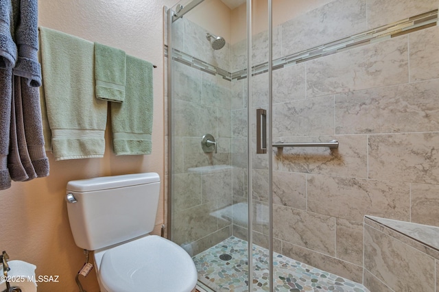 bathroom featuring toilet and a shower with shower door